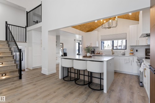 Open-concept kitchen featuring an island with seating, white cabinetry, and light-colored countertops - 38 Woodcrest Avenue, St. Albert, AB - Indoor Photo Showing Kitchen With Upgraded Kitchen