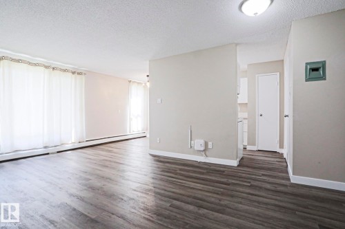 Spacious room featuring wood-finish flooring, light grey wall paint, and white baseboards - 118 7220 144 Avenue, Edmonton, AB - Indoor Photo Showing Other Room