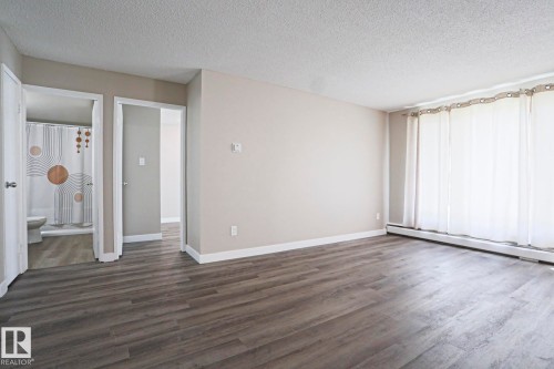 Spacious room featuring wood-finish flooring, light neutral wall tones, and white trim - 118 7220 144 Avenue, Edmonton, AB - Indoor Photo Showing Other Room
