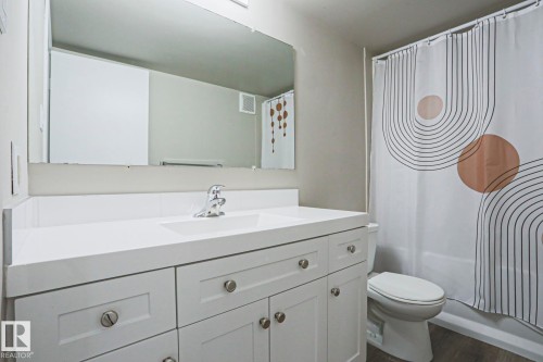 Bathroom featuring a white vanity with integrated sink, chrome faucet, and a large wall mirror - 118 7220 144 Avenue, Edmonton, AB - Indoor Photo Showing Bathroom