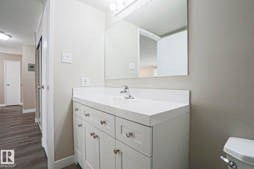 Bathroom featuring a white vanity with brushed nickel hardware, a rectangular undermount sink, and a white countertop with an integrated backsplash - 118 7220 144 Avenue, Edmonton, AB - Indoor Photo Showing Bathroom