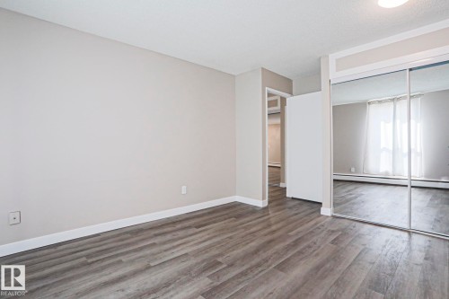Spacious room featuring wood-finish flooring, light neutral wall tones, and white baseboards - 118 7220 144 Avenue, Edmonton, AB - Indoor Photo Showing Other Room