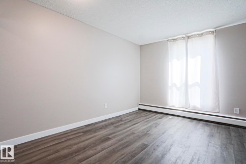Room featuring wood-finish flooring, light grey walls, and white baseboards - 118 7220 144 Avenue, Edmonton, AB - Indoor Photo Showing Other Room