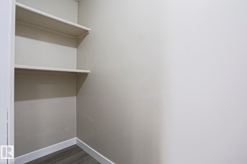 Built-in shelving unit featuring two shelves, neutral wall paint, white baseboards, and wood-finish flooring - 118 7220 144 Avenue, Edmonton, AB - Indoor With Storage