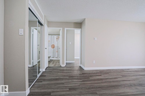 Spacious room featuring wood-finish flooring, light neutral wall paint, and white baseboards - 118 7220 144 Avenue, Edmonton, AB - Indoor Photo Showing Other Room