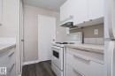 Galley-style kitchen featuring white cabinetry with modern pulls, a white electric range, and laminate countertops - 118 7220 144 Avenue, Edmonton, AB  - Indoor Photo Showing Kitchen 