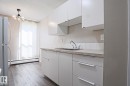 Kitchen featuring white cabinetry with integrated hardware, a double basin stainless steel sink, and a light-toned countertop - 118 7220 144 Avenue, Edmonton, AB  - Indoor Photo Showing Kitchen 