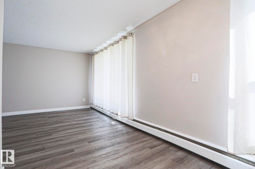 Spacious room with wood-finish flooring, light neutral wall paint, and white baseboards - 118 7220 144 Avenue, Edmonton, AB - Indoor Photo Showing Other Room