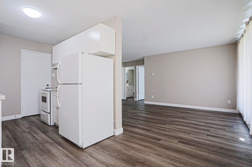 Open-concept living area featuring wood-finish flooring and neutral-toned walls - 118 7220 144 Avenue, Edmonton, AB - Indoor