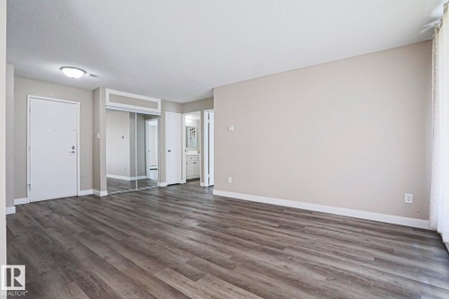 Spacious room featuring wood-finish flooring, light neutral wall tones, and white baseboards - 118 7220 144 Avenue, Edmonton, AB - Indoor Photo Showing Other Room