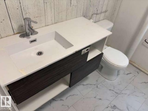 Modern vanity featuring an integrated sink with a chrome faucet, dark wood-finish cabinetry, and an open storage shelf - 10730 92 Street, Edmonton, AB - Indoor Photo Showing Bathroom