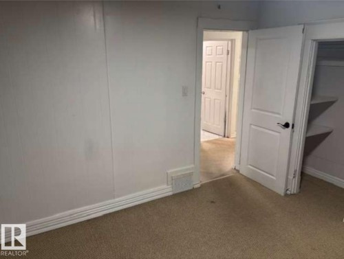 Carpeted room featuring white panel walls, white baseboards, and a white interior door with a black handle - 10730 92 Street, Edmonton, AB - Indoor Photo Showing Other Room