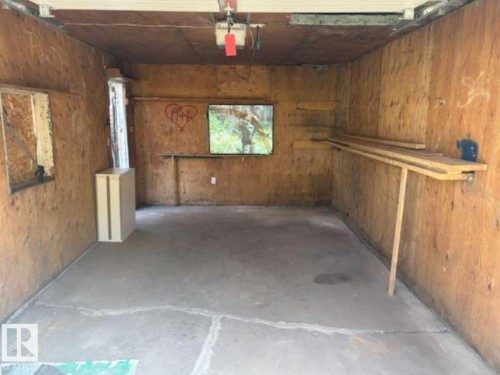 Garage interior featuring plywood wall finishes, concrete flooring, and built-in shelving - 10730 92 Street, Edmonton, AB - Indoor