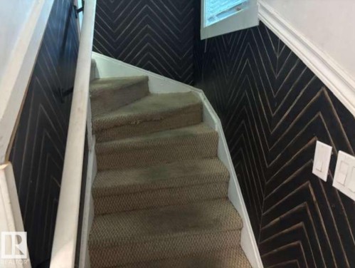 Staircase featuring carpeted treads and risers, white painted balustrade, and a dark accent wall with a chevron pattern - 10730 92 Street, Edmonton, AB -  Photo Showing Other Room