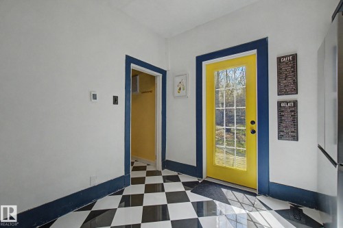 Black and white checkerboard flooring with a bright yellow multi-pane door - 11512 122 St, Edmonton, AB - Indoor Photo Showing Other Room