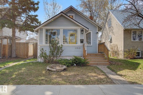 Light blue siding exterior featuring a prominent front porch with wood stairs and railing - 11512 122 St, Edmonton, AB - Outdoor With Facade