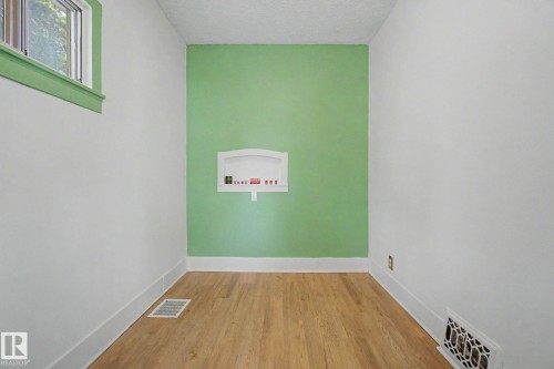 Light wood-finish flooring complemented by white baseboards and walls - 11512 122 St, Edmonton, AB - Indoor Photo Showing Other Room
