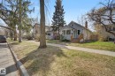 Light blue siding exterior with a contrasting brick chimney and a covered front porch featuring multiple windows - 11512 122 St, Edmonton, AB  - Outdoor With Facade 