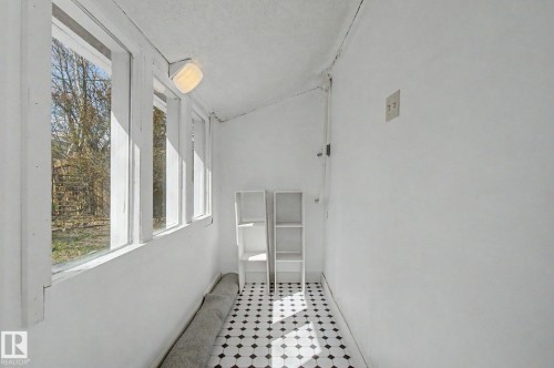 Sunroom featuring a black and white diamond pattern floor tile, a full wall of vertical windows, and a flush-mount ceiling light fixture - 11512 122 St, Edmonton, AB - Indoor Photo Showing Other Room