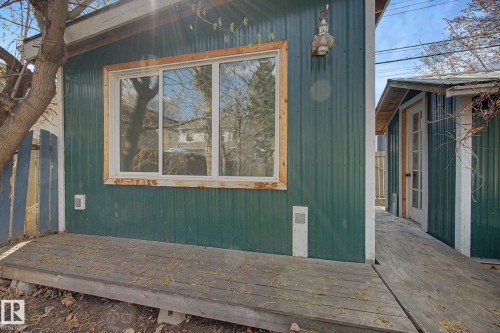 Corrugated metal siding in a deep green hue, framed by a wood-finish deck - 11512 122 St, Edmonton, AB - Outdoor With Exterior