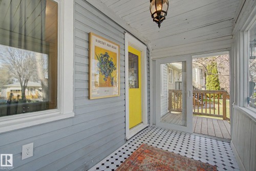 Enclosed porch featuring a yellow entry door, black and white hexagon tile flooring, and white paneled walls and ceiling - 11512 122 St, Edmonton, AB - Outdoor With Exterior