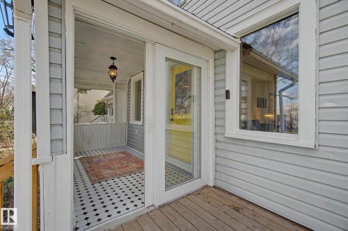 Inviting screened porch featuring black and white patterned tile flooring, a hanging lantern light fixture, and white painted railings - 11512 122 St, Edmonton, AB - Outdoor With Exterior