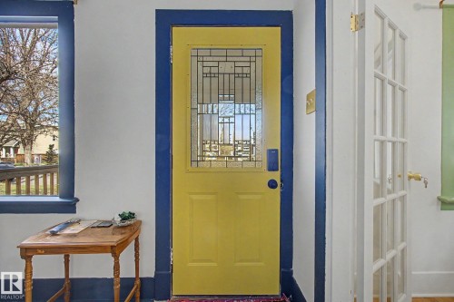 Entryway featuring a bright yellow door with decorative glass inserts, deep blue trim, a transom window, and an adjacent French door - 11512 122 St, Edmonton, AB - Indoor Photo Showing Other Room