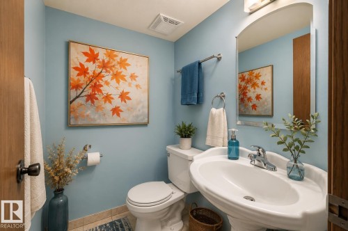 Powder room featuring a pedestal sink with a chrome faucet, a wall-mounted mirror, and light blue walls - 17313 60 Avenue, Edmonton, AB - Indoor Photo Showing Bathroom