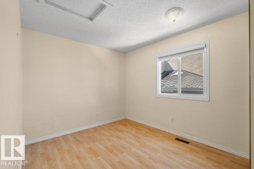 This room features light wood-style flooring, a window with a white frame and roller blind, and a ceiling light fixture - 17313 60 Avenue, Edmonton, AB - Indoor Photo Showing Other Room