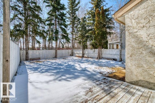 The property features an extensive yard with a white fence, mature trees, and a wooden deck - 17313 60 Avenue, Edmonton, AB - Outdoor