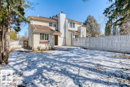 The property features a private yard with a white picket fence, a patio area, and mature trees - 17313 60 Avenue, Edmonton, AB - Outdoor