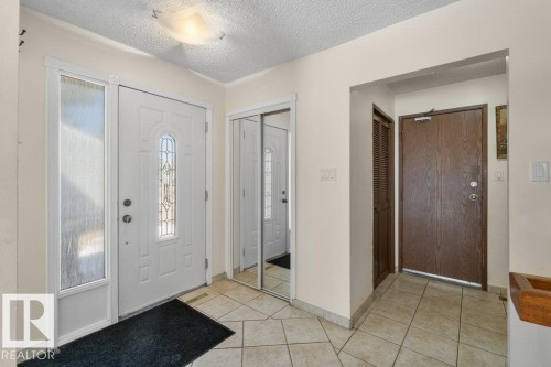 Entrance featuring tiled flooring, a white main entry door with decorative glass, and a mirrored closet door - 17313 60 Avenue, Edmonton, AB - Indoor Photo Showing Other Room