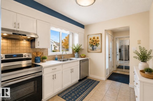 Modern kitchen featuring white cabinetry, stainless steel appliances, a white countertop, and a tiled backsplash - 17313 60 Avenue, Edmonton, AB - Indoor Photo Showing Kitchen With Double Sink