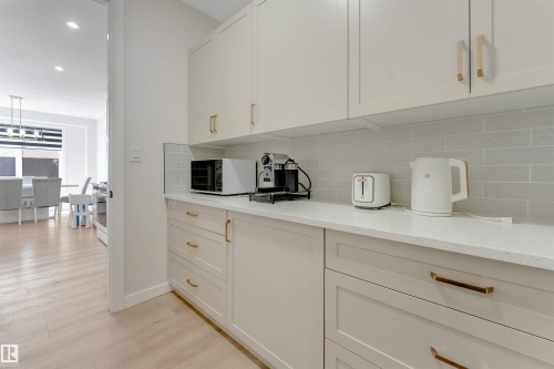 Kitchenette featuring light-toned cabinetry with gold-toned hardware, a light quartz-finish countertop, and a subway tile backsplash - 7007 169 Avenue Nw, Edmonton, AB - Indoor Photo Showing Kitchen
