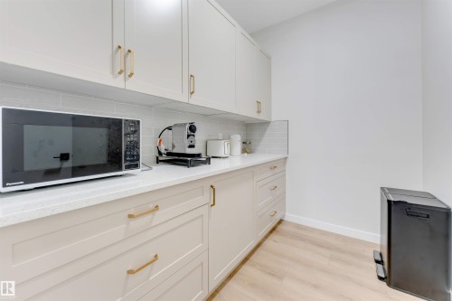 Kitchenette featuring light-toned cabinetry with gold-finish hardware, light-toned countertops, and a subway tile backsplash - 7007 169 Avenue Nw, Edmonton, AB - Indoor Photo Showing Kitchen