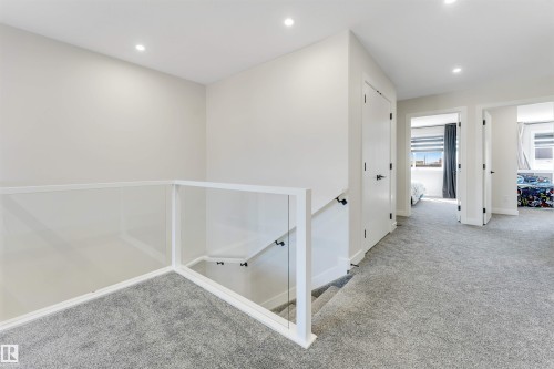 Upper-level hallway featuring plush gray carpeting, recessed lighting, and a contemporary glass and white railing system - 7007 169 Avenue Nw, Edmonton, AB - Indoor Photo Showing Other Room
