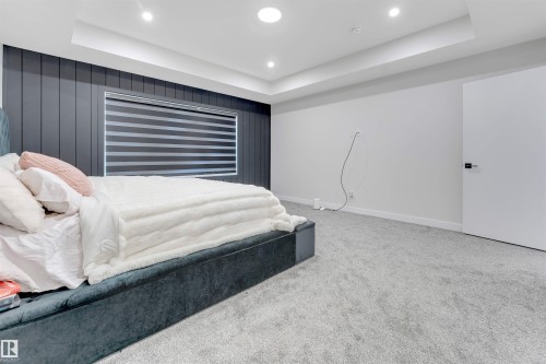 Recessed lighting illuminates a room featuring gray vertical paneling, a large window with horizontal blinds, and a white interior door with a matte black handle - 7007 169 Avenue Nw, Edmonton, AB - Indoor Photo Showing Bedroom