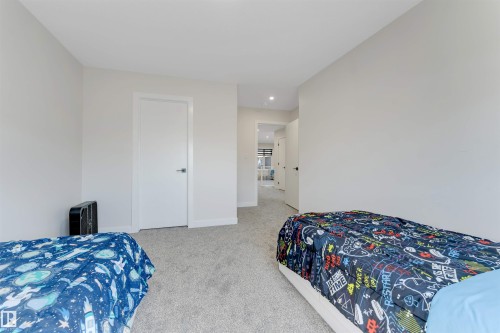 Carpeted room with light-toned walls and trim, featuring a white solid-core door with a brushed nickel handle - 7007 169 Avenue Nw, Edmonton, AB - Indoor Photo Showing Bedroom