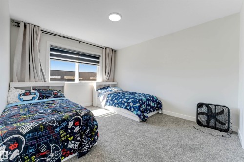 Bedroom featuring light gray wall paint, gray carpet flooring, a window with roller blinds and drapery, and a flush-mount ceiling light - 7007 169 Avenue Nw, Edmonton, AB - Indoor Photo Showing Bedroom