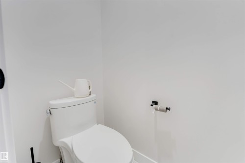 White toilet with chrome flush lever, set against bright white walls - 7007 169 Avenue Nw, Edmonton, AB - Indoor