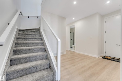Carpeted staircase with glass panel railing and track lighting - 7007 169 Avenue Nw, Edmonton, AB - Indoor Photo Showing Other Room