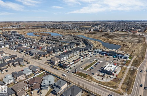 Aerial perspective showcasing a developed residential neighborhood with mixed architectural styles, commercial buildings, and natural water features - 7007 169 Avenue Nw, Edmonton, AB - Outdoor With View
