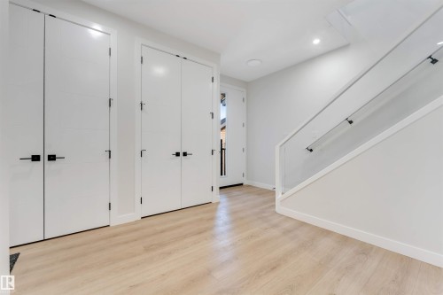 Entryway featuring light wood-finish flooring, white walls, and a modern staircase with glass railing - 7007 169 Avenue Nw, Edmonton, AB - Indoor Photo Showing Other Room