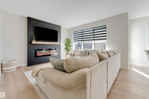Modern living area featuring a horizontal shiplap accent wall with an integrated electric fireplace and a wall-mounted display - 7007 169 Avenue Nw, Edmonton, AB - Indoor Photo Showing Living Room With Fireplace