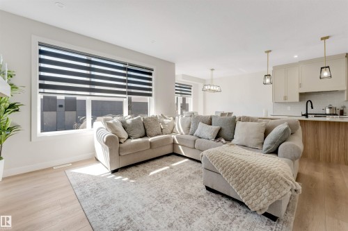 Open-concept living area with light wood-finish flooring, white walls, and large windows with horizontal blinds - 7007 169 Avenue Nw, Edmonton, AB - Indoor Photo Showing Living Room
