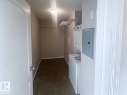 Dedicated laundry area featuring a stacked washer and dryer unit, overhead shelving, and neutral wall tones - 