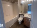 Bathroom featuring a combined tub and shower unit, a vanity with wood-finish cabinetry, a built-in sink, a large mirror, and overhead lighting - 6120 7331 South Terwillegar Drive Nw, Edmonton, AB  - Indoor Photo Showing Bathroom 