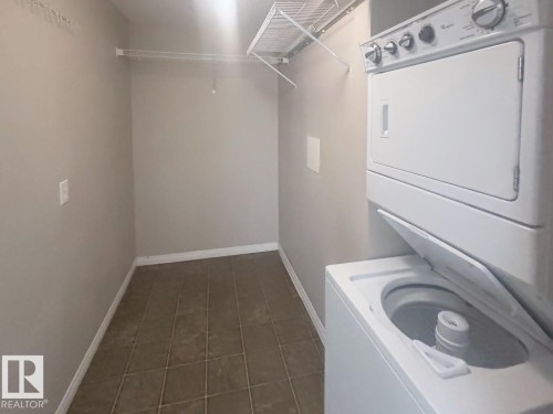 Dedicated laundry area featuring a stacked washer and dryer unit - 6120 7331 South Terwillegar Drive Nw, Edmonton, AB - Indoor Photo Showing Laundry Room