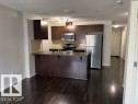 Kitchen featuring dark wood-finish cabinetry, stainless steel appliances, a breakfast bar, recessed lighting, and dark wood-finish flooring - 118 3357 16A Avenue, Edmonton, AB 