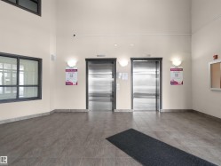 Lobby area featuring dual stainless steel elevators, neutral wall tones, and large format floor tiles - 